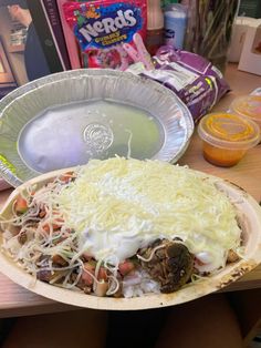 a pizza sitting on top of a wooden table next to a bowl of noodles and sauce