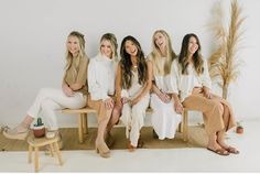 four women are sitting on a bench and smiling