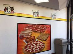 a large pizza advertisement hangs on the wall next to a trash can