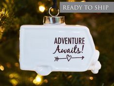 an ornament hanging from a christmas tree with the words adventure awaits written on it