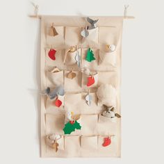 a white wall hanging with christmas decorations on clothes pins and pegs attached to it