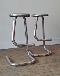 two chrome stools sitting on top of a wooden floor