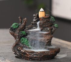 a small fountain with a pencil sticking out of it's center, on top of a table