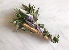 a bouquet of flowers tied to a wooden stick on a marble counter top with greenery