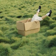 a person laying on the ground in a cardboard box