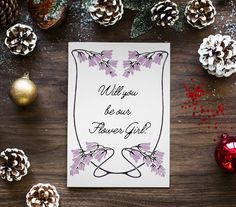 a card with the words will you be our flower girl? surrounded by pine cones and christmas decorations