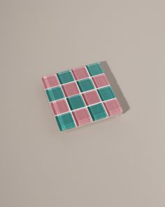 a pink and green square shaped tile on a gray surface