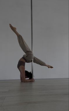 a man is doing a handstand on the floor in front of a pole