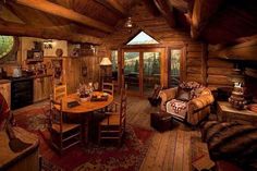 a rustic log cabin with wood floors and walls, wooden ceilinging, two couches, an oval dining table in the center