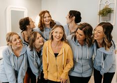 a group of women standing next to each other in front of a mirror smiling at the camera