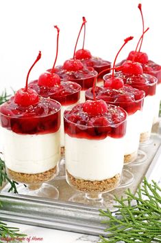 small cakes with strawberries on top are sitting on a platter and decorated with greenery