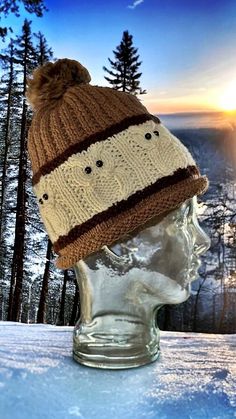 a knitted hat sitting on top of a glass head in the middle of snow