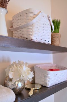 some baskets are sitting on top of shelves with flowers and candles next to each other