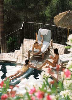 two women and a man relaxing in an outdoor hot tub with flowers on the deck