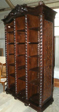 an old wooden bookcase with intricate carvings on the front and sides, in a warehouse