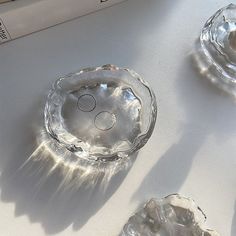 three crystal bowls sitting on top of a table next to books and an open book