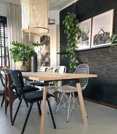 a dining room table and chairs with plants on the wall behind it in front of a window