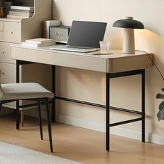 a laptop computer sitting on top of a wooden desk next to a lamp and chair