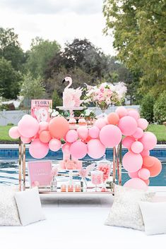 a pink flamingo themed birthday party with balloons and cake on a table next to a pool