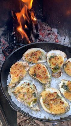 a pan filled with oysters sitting on top of rice next to an open fire