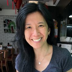 a woman with long black hair is smiling for the camera in a restaurant or bar