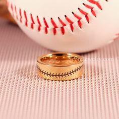 two gold wedding bands sitting next to a baseball