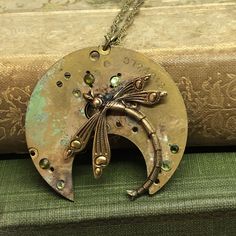 a necklace with an insect on it sitting on top of a book