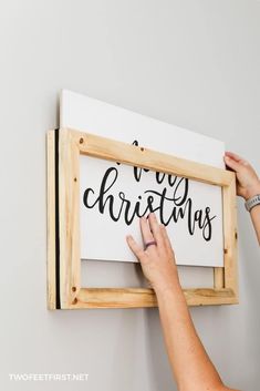 a woman is holding up a sign that says merry christmas on it, with the word written in cursive font