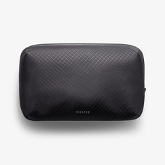 a black cosmetic bag sitting on top of a white wall