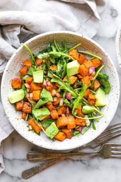 a white bowl filled with greens and sweet potato salad