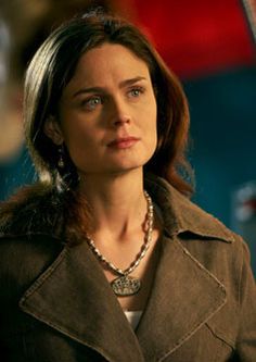 the woman is wearing a brown jacket and necklace