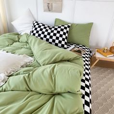 a bed with green sheets and checkered pillows