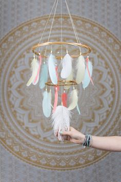 a person is holding up a dream catcher with feathers hanging from it's sides