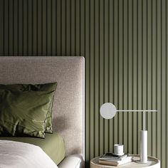 a bedroom with green striped walls and a white nightstand next to the bed in front of it