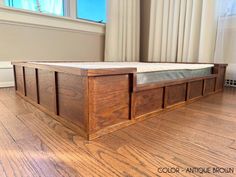 a wooden bed frame sitting on top of a hard wood floor next to a window