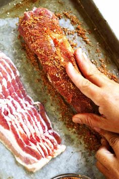 A hand rubbing the brown sugar mixture into a pork tenderloin. A stack of bacon is sitting next to it. Pork Tenderloin Recipes Teriyaki, Pork Tenderloin Recipes In Oven Bacon Wrapped, Perfect Pork Tenderloin Pioneer Woman, Balsamic Brown Sugar Pork Tenderloin, Pork Tenderloin Wrapped In Bacon Recipes, Pork Bacon Recipe, Applewood Bacon Pork Tenderloin, Bacon Brown Sugar Pork Tenderloin, Ways To Cook A Pork Tenderloin