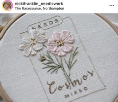 a close up of a cross stitch on a piece of cloth with flowers in it