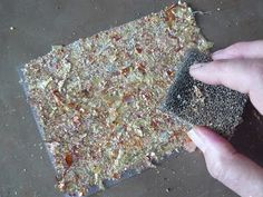 a hand is holding a sponge over a piece of food that has been placed on the ground