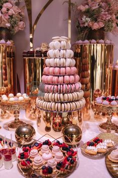 desserts and pastries are displayed on a table in front of gold vases