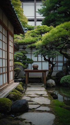 a stone path leading to a small table in the middle of a garden with trees and rocks