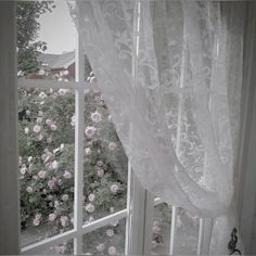 an open window with white curtains and pink flowers