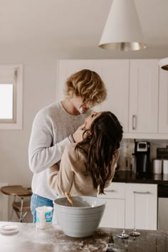 two women standing in a kitchen next to each other and one is holding her head over the bowl