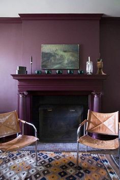 two chairs sitting in front of a fire place next to a painting on the wall