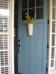 a blue door with white shutters and a planter