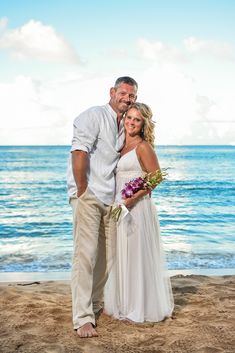 a man and woman are standing on the beach with their arms around each other as they pose for a photo