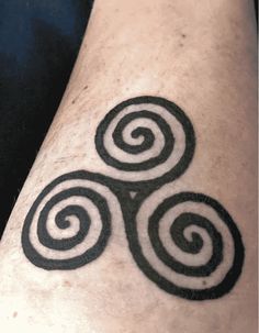 a black and white photo of a tattoo on someone's arm with spiral designs