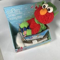 a sesame street stuffed animal in a box with music notes on its ear and eyes