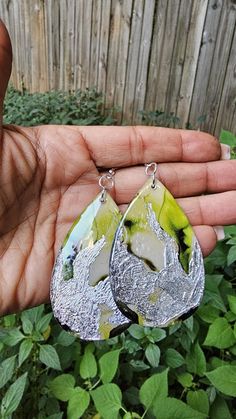 Highlights: 🖐️Made by: Shine Expressions ✨Materials: Resin, Wood, Alcohol Ink, Silver Leaf 🖌️Style: Geometric, Modern 📨Shipped from Georgia!  Shorter shipping distances are kinder to the planet.   📐Drop length: 3-3.25"    Width:  1.25-1.5" About this item: Turn heads with these bold lime green and silver teardrop earrings, designed for the woman who loves to make a statement. The vibrant lime green exudes energy, renewal, and confidence, while the silver metallic accents add a splash of edgy Green And Silver, Paper Jewelry, Earrings Unique, Metallic Accents, Silver Leaf, Unique Earrings, Resin Jewelry, Alcohol Ink, Teardrop Earrings