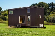 a tiny house on wheels parked in the grass