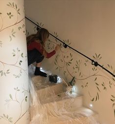 a woman is painting the stairs with white paint and black string lights on each handrail